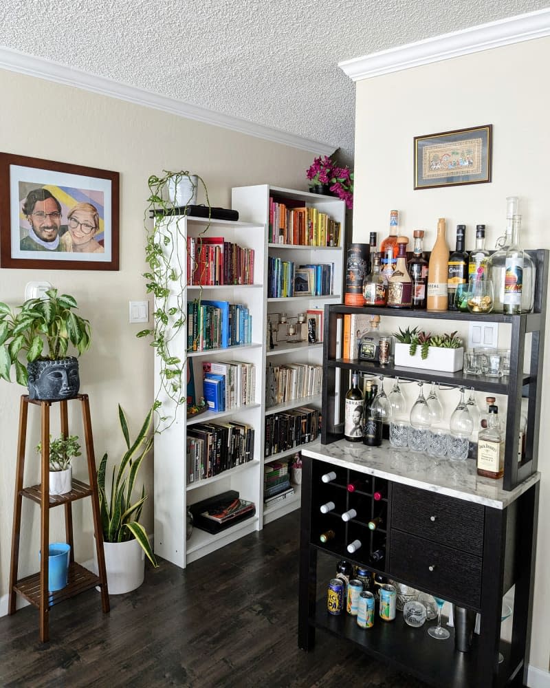 Area of beige dining room with bar, bookshelves, and plants