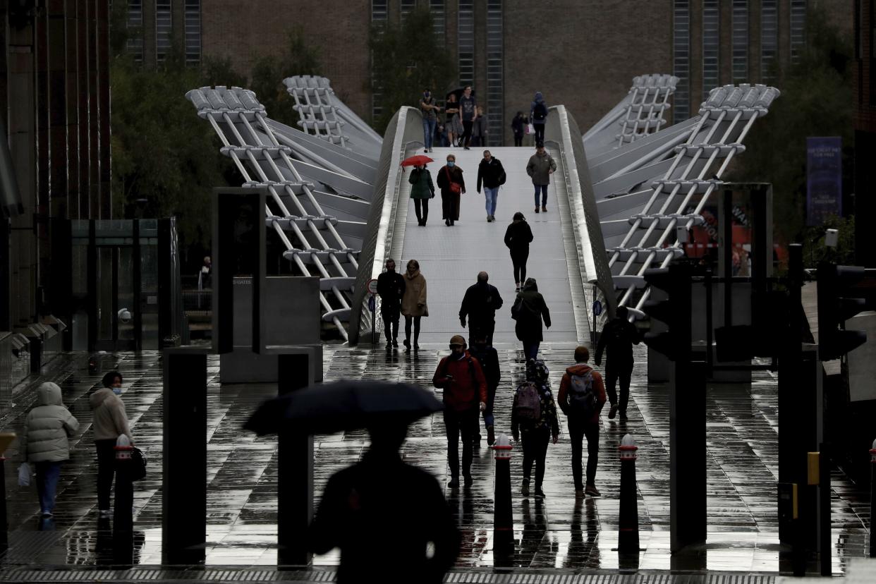 People walk across the London Millennium Footbridge in London, England on Thursday, Oct. 15, 2020. London will be moved into a coronavirus Tier 2 lockdown as part of the British government's new alert system for rising case numbers, starting midnight local time on Friday night into Saturday. The new restrictions will include stopping different households from mixing indoors and people should aim to avoid public transport if they can.