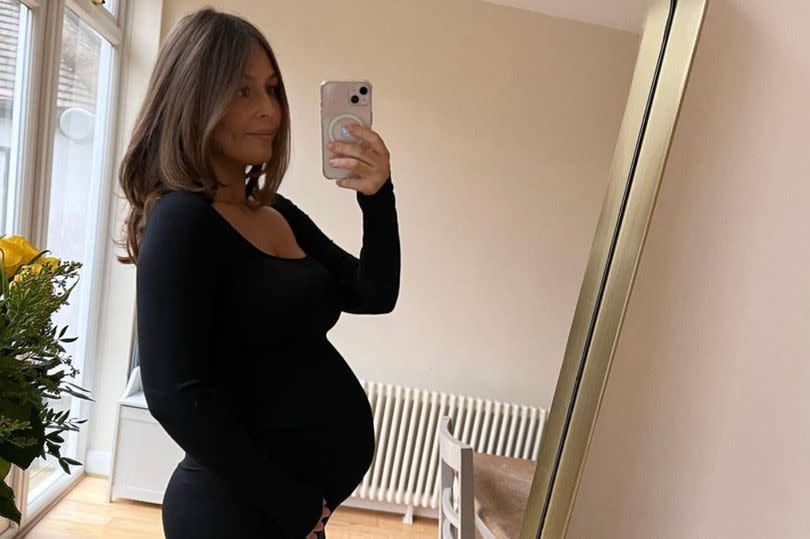 Cristy Sharp showing off her baby bump in a black dress