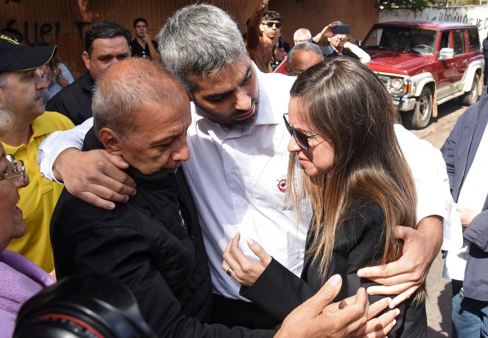 The president of Paraguayan club Guarani, Juan Alberto Acosta (L), gives his condolences to the brother and the wife of Paraguayan anti-drug prosecutor Marcelo Pecci, Francisco Pecci (C) and Claudia Aguilera, respectively, before his funeral, in Asuncion on May 15, 2022. / Credit: DANIEL DUARTE/AFP via Getty Images
