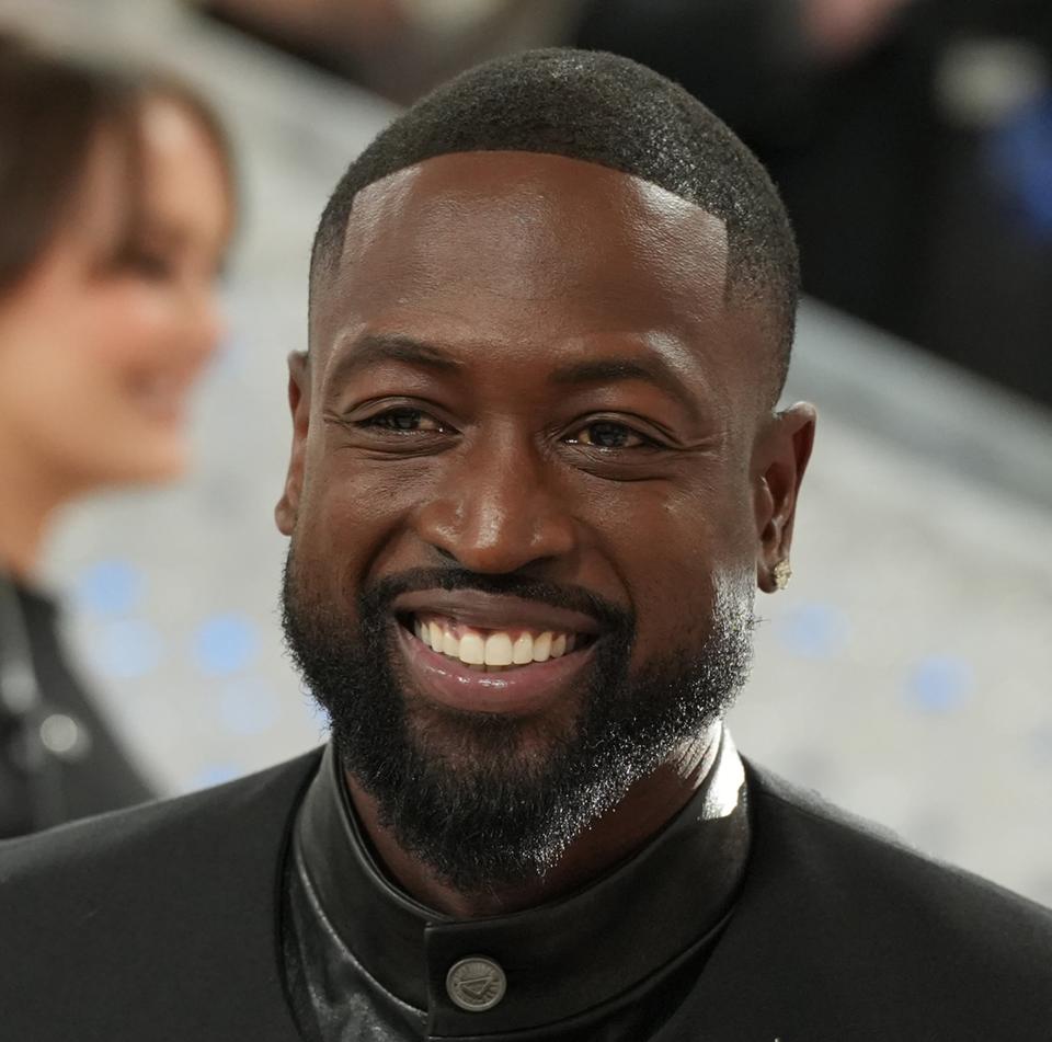 Dwyane in a tuxedo with a unique crescent accessory, leather gloves, attending an event