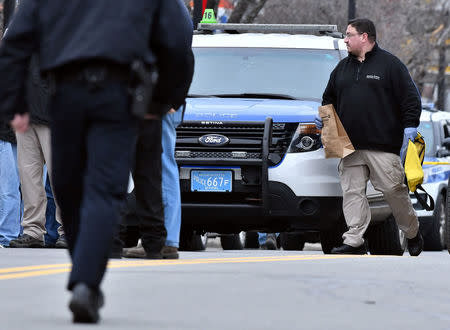 A Boston Police crime scene investigator carries evidence bags at the scene after a burning propane tank was left near an unoccupied police cruiser in Boston, Massachusetts, U.S., January 20, 2017. REUTERS/Josh Reynolds