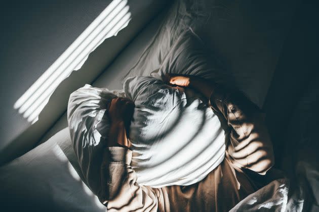 Woman suffering from depression. Woman covering her face with pillow. (Photo: Maria Korneeva via Getty Images)