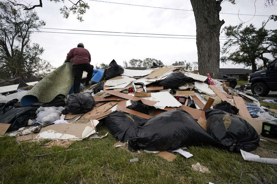 Khalif Kinnie throws debris on a pile from a heavily damaged home he was hired to gut, in the aftermath of Hurricane Laura and Hurricane Delta, in Lake Charles, La., Friday, Dec. 4, 2020. (AP Photo/Gerald Herbert)