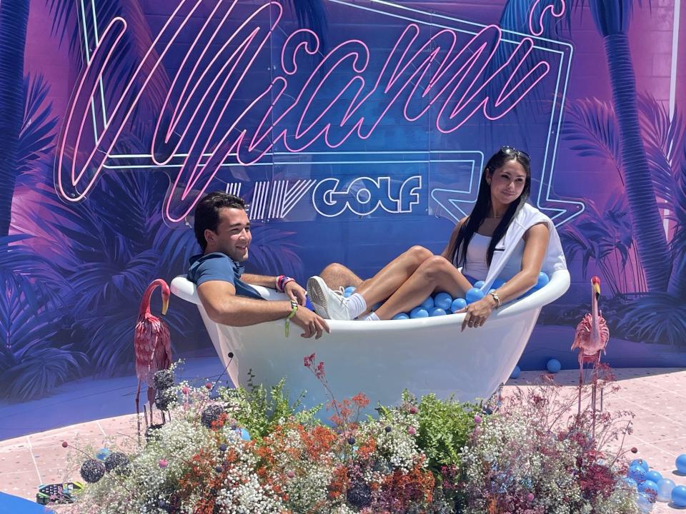 A couple pose for a photo at LIV Golf Miami sitting plastic-ball bubble bath.