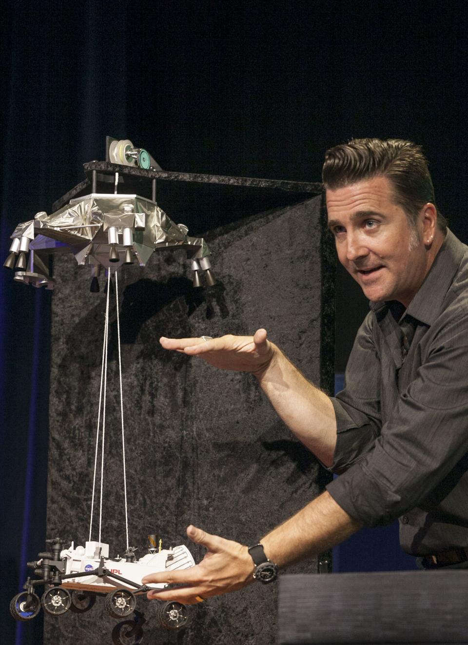 FILE - In this Thursday, Aug. 2, 2012 file photo, Adam Steltzner, Mars Science Laboratory's entry, descent and landing phase leader at JPL uses a scale model to explain the process for the Curiosity rover during news briefing at NASA's Jet Propulsion Laboratory in Pasadena, Calif. NASA's Curiosity rover is still on the move after six years, with more than 12 miles (20 kilometers) on its odometer. (AP Photo/Damian Dovarganes, File)