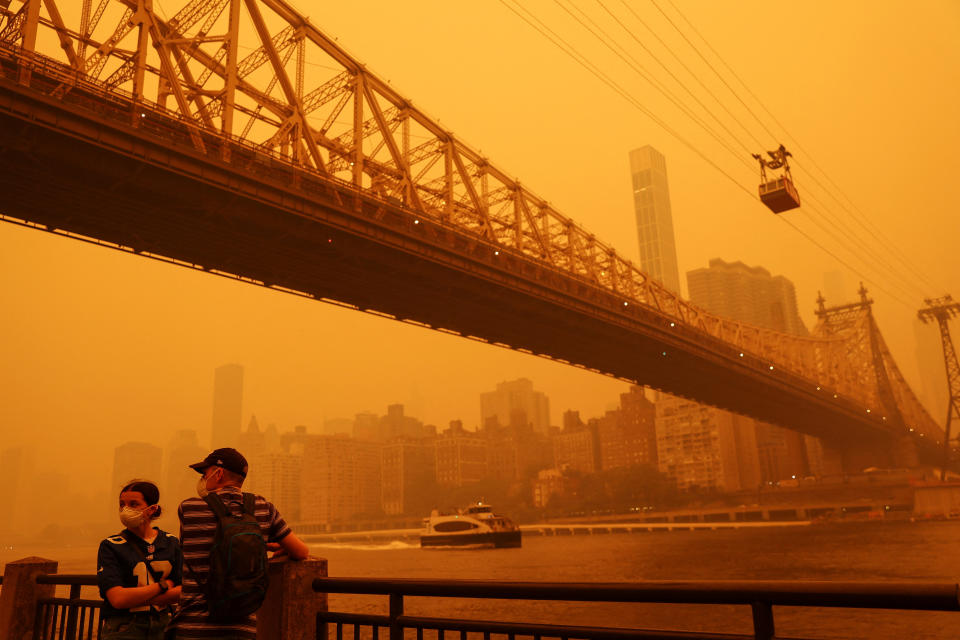 <p>People wear protective masks as the Roosevelt Island Tram crosses the East River while haze and smoke from the Canadian wildfires shroud the Manhattan skyline in the Queens Borough New York City, U.S., June 7, 2023. REUTERS/Shannon Stapleton</p> 