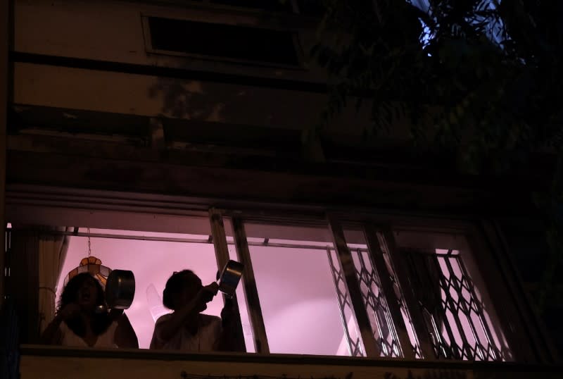 Women bang pots at the window of their house as they protest against Brazilian President Jair Bolsonaro during the coronavirus disease (COVID-19) outbreak in Rio de Janeiro