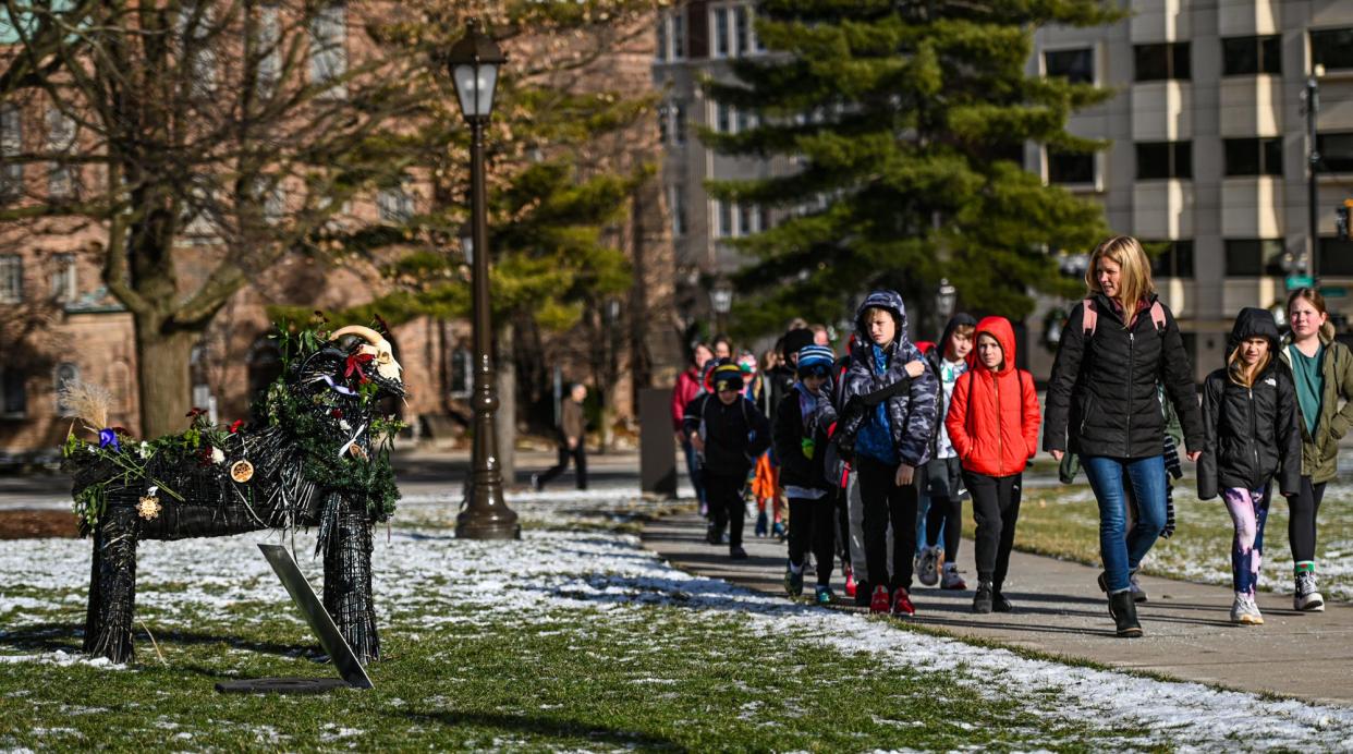 A group of students heading into the state Capitol on a field trip check out the "yule goat" display on the Capitol lawn Tuesday, Dec. 19, 2023.