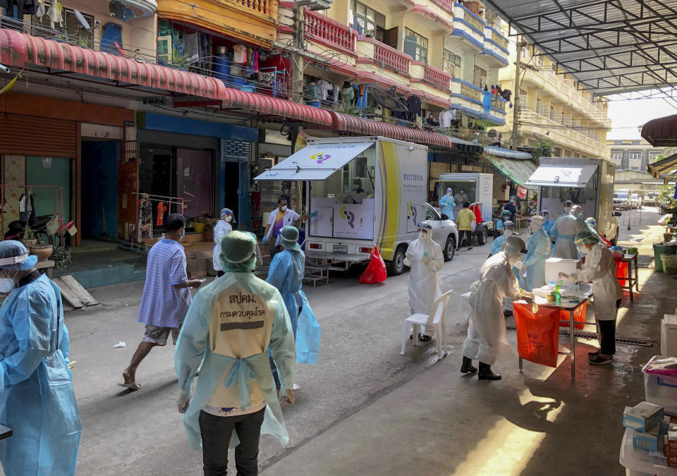 Health workers in protective clothing conduct screening for COVID-19 in Samut Sakhon, south of Bangkok, Thailand, Sunday, Dec. 20, 2020. Thailand reported more than 500 new coronavirus cases on Saturday, the highest daily tally in a country that had largely brought the pandemic under control. (AP Photo/Jerry Harmer)