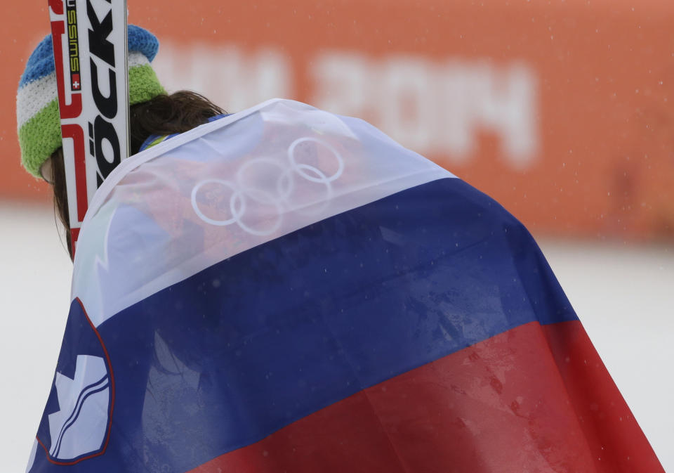 Women's giant slalom gold medal winner Tina Maze of Slovenia leaves the podium draped in her national flag after a flower ceremony at the Sochi 2014 Winter Olympics, Tuesday, Feb. 18, 2014, in Krasnaya Polyana, Russia.