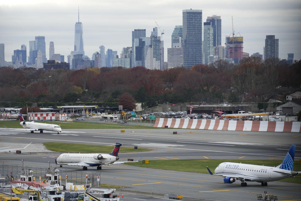 The New York City skyline is seen behind planes waiting to take off at LaGuardia Airport in New York, Wednesday, Nov. 22, 2023. (AP Photo/Seth Wenig)