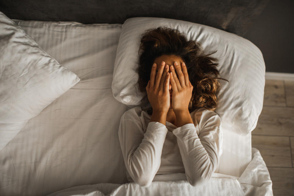 a woman laying in bed with her hands to her face