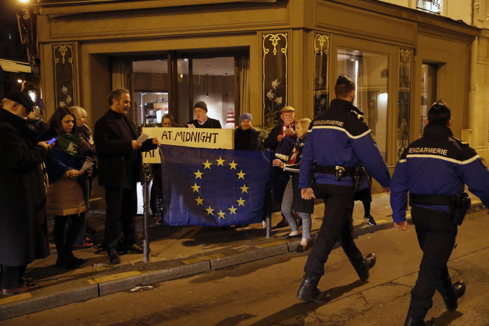 French gendarmes walk by as British living in France attend a gathering to express their sprit of Europe despite the withdrawal Brexit agreement and the UK's departure from the EU, in a street closed to the British Embassy in Paris, Friday, Jan. 31, 2020. Britain leaves the European Union after 47 years, leaping into an unknown future in a historic blow to the bloc. (AP Photo/Francois Mori)