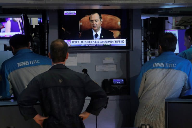 A screen broadcasts impeachment hearing as traders work on the floor at the NYSE in New York