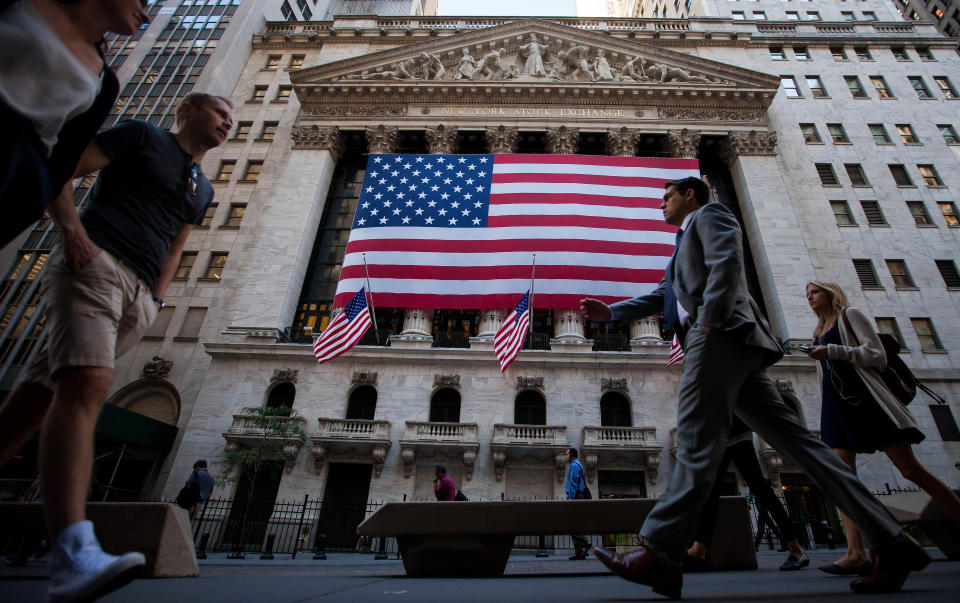 Pedestrians walk past an American flag displayed outside of the New York Stock Exchange (NYSE) in New York, U.S. Photographer: Michael Nagle/Bloomberg