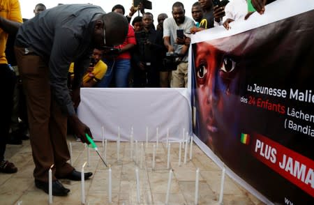 A man lights a candle during a remembrance ceremony at the Monument de la Paix in Bamako