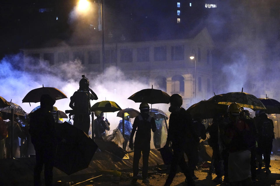 Protesters stand outside of Hong Kong Polytechnic University after police gave protesters an ultimatum to leave the campus in Hong Kong, early Monday, Nov. 18, 2019. Police launched a late-night operation Sunday to try to flush about 200 protesters out of a university campus on a day of clashes in which an officer was hit in the leg with an arrow and massive barrages of tear gas and water cannons were fired. (AP Photo/Vincent Yu)