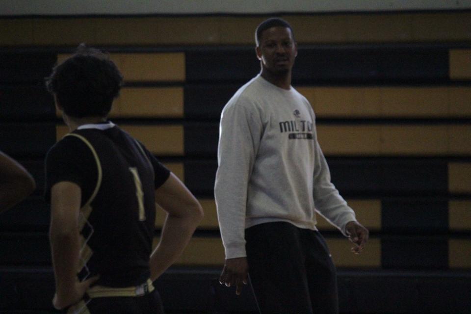 Milton boys basketball assistant coach Isaiah Jones (grey sweatshirt) keeps an eye on practice on Monday, Dec. 18, 2023. Jones is acting as head coach while head coach Joey Nieves is out for the week for a personal matter.