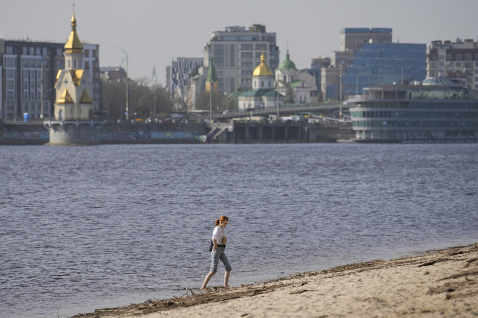 A woman enjoys a warm afternoon on the bank of the Dniepr River in Kyiv, Ukraine, Tuesday, April 2, 2024. (AP Photo/Vadim Ghirda)