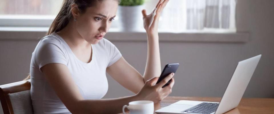 Mad young female annoyed with scam or spam messages on smartphone