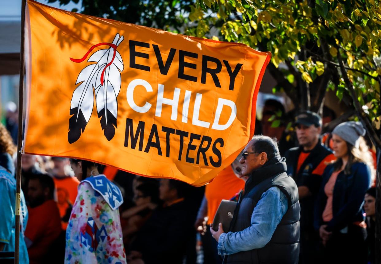 A flag flies as people attend during National Day for Truth and Reconciliation ceremonies in Calgary, Alta. on Sept. 30, 2022.  (Jeff McIntosh/The Canadian Press - image credit)