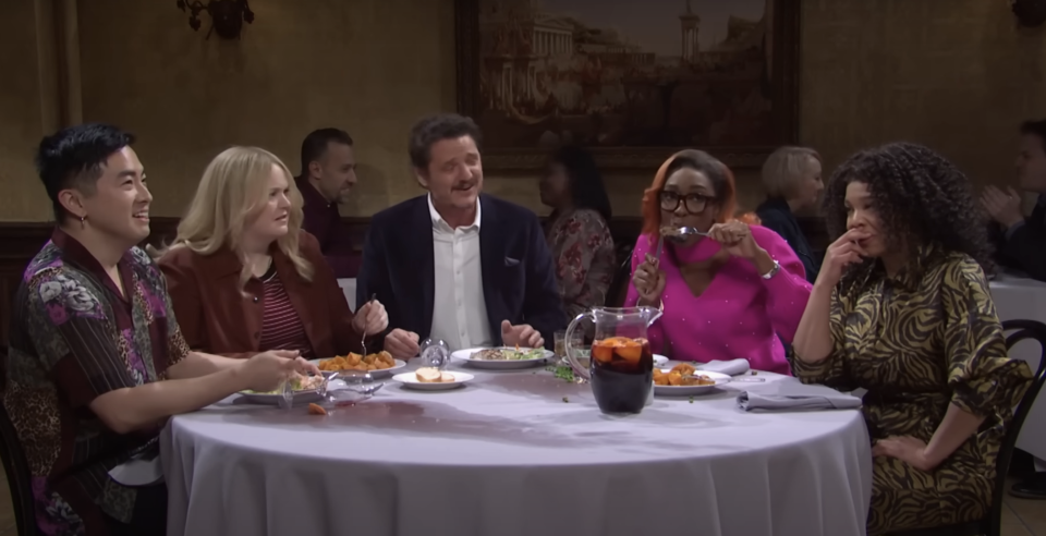 Bowen Yang, Sarah Paulson, Pedro Pascal, Ego Nwodim, and a woman sitting at a restaurant table, laughing and eating together