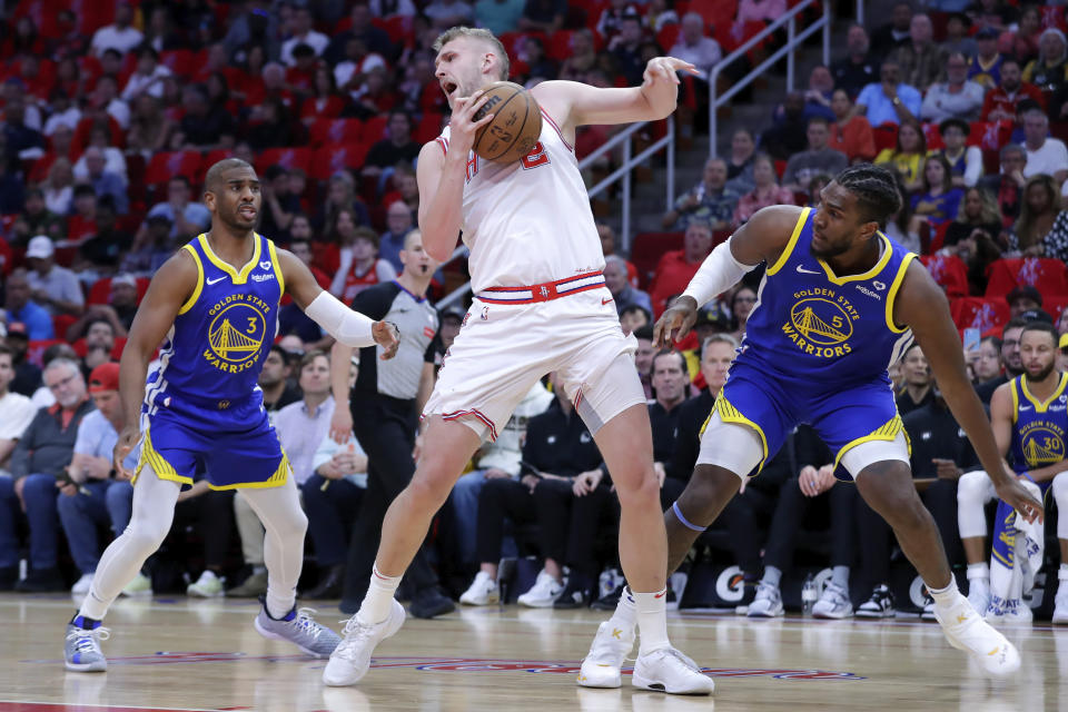 Houston Rockets center Jock Landale, center, pulls in a rebound between Golden State Warriors guard Chris Paul, left, and forward Kevon Looney, right, during the first half of an NBA basketball game Thursday, April 4, 2024, in Houston. (AP Photo/Michael Wyke)