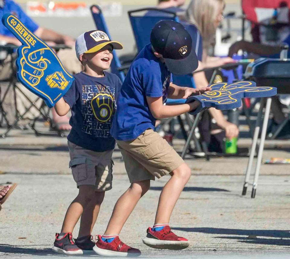 Jameson Braasmka, 4, left, and Jackson Braasmka, 5, play with their foam fingers Tuesday, Oct. 3, 2023, in the Brewers 1 lot at American Family Field in Milwaukee. The two brother love baseball and their favorite part about tailgating is the food. Ebony Cox / Milwaukee Journal Sentinel