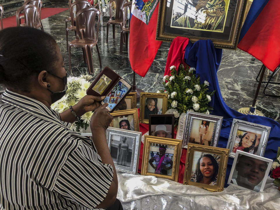 A woman takes a photo of the images of the 11 Haitian women who died last month when the overloaded boat they were in capsized, at a church in San Juan, Puerto Rico, Wednesday, June 15, 2022. The boat was carrying an estimated 60 to 75 migrants, of which eleven were found dead, at least a dozen still missing and 38 rescued. (AP Photo/Dánica Coto)