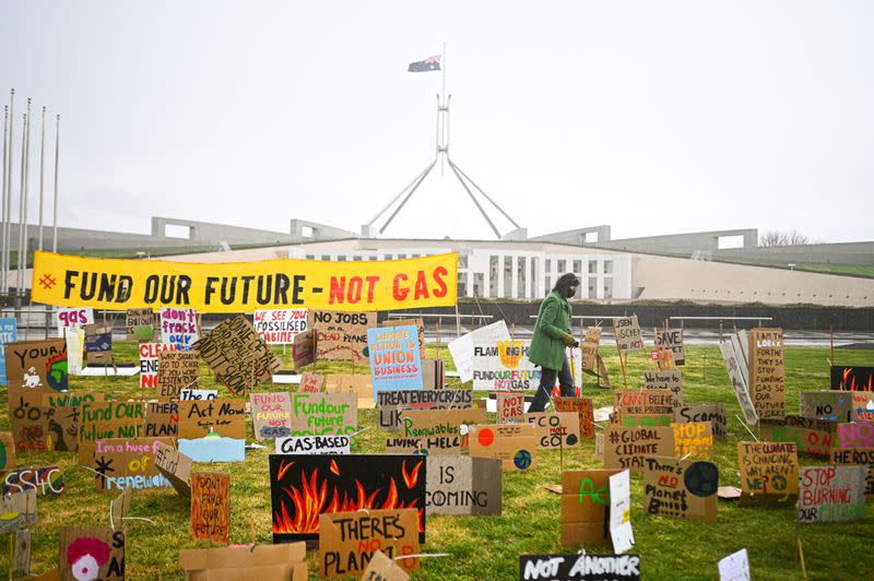 A school student walks amongst signs during a student climate protest outside Parliament House in Canberra