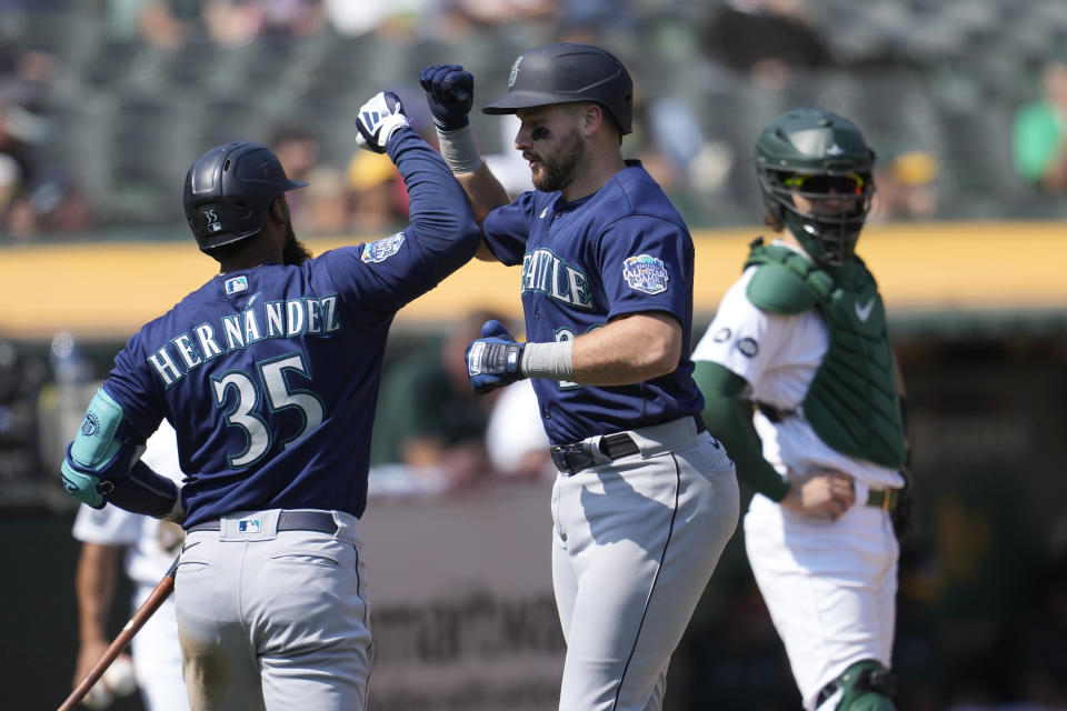 Seattle Mariners' Cal Raleigh, middle, is congratulated by Teoscar Hernandez (35) after hitting a home run as Oakland Athletics catcher Tyler Soderstrom, right, looks on during the fifth inning of a baseball game in Oakland, Calif., Wednesday, Sept. 20, 2023. (AP Photo/Jeff Chiu)