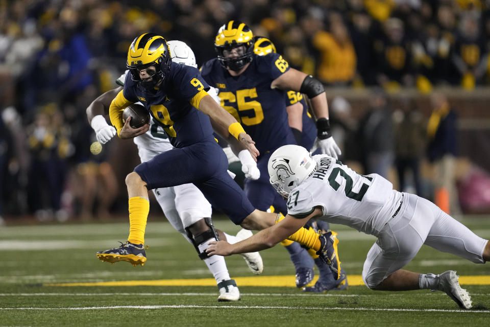 Michigan quarterback J.J. McCarthy (9) runs from Michigan State linebacker Cal Haladay (27) in the first half of an NCAA college football game in Ann Arbor, Mich., Saturday, Oct. 29, 2022. (AP Photo/Paul Sancya)