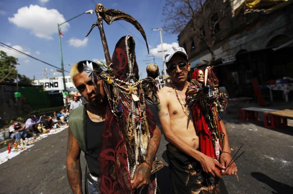 Followers of La Santa Muerte (The Saint of Death), a cult figure often depicted as a skeletal grim reaper, pose for a photograph at the saint's altar in Tepito, Mexico City January 1, 2013. Followers gather at the altar at the start of a new year, and subsequently on the first of each month, to leave offerings of apples, flowers, cigarettes, coloured candles and tequila to thank her for granted favours or to ask for new ones.