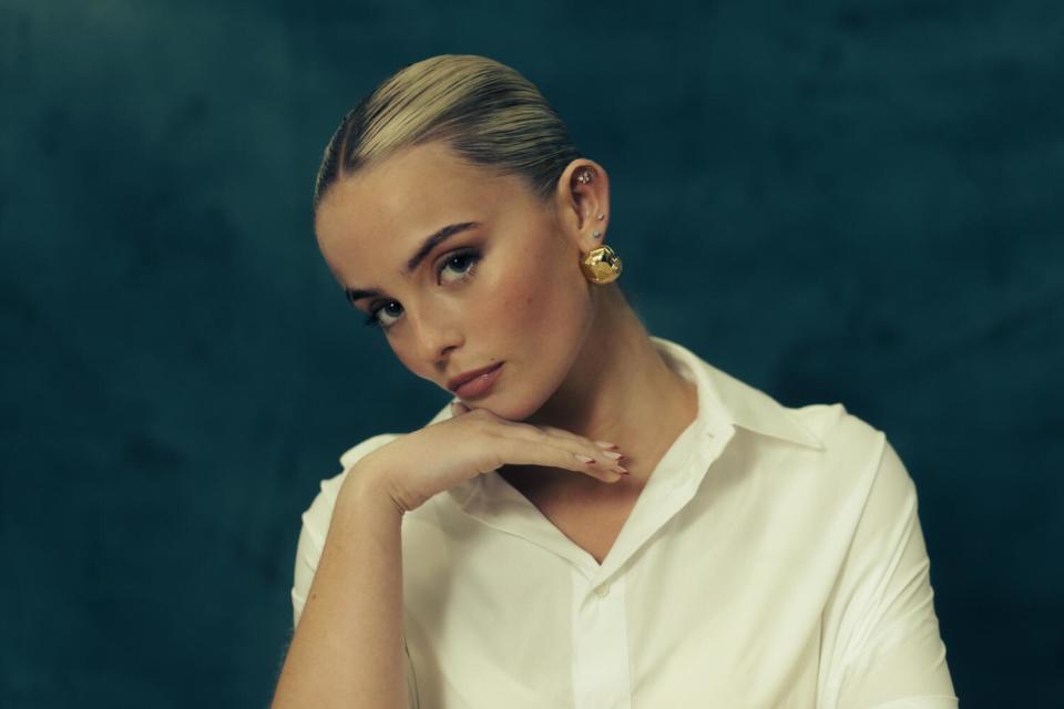 a young woman posing in front of a bluish backdrop