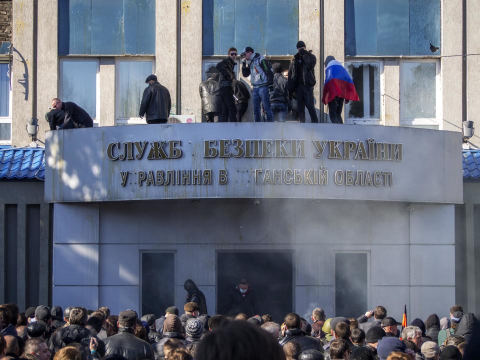 Activistas prorrusos aparecen en el balcón de la oficina regional del Servicio de Seguridad en Luhansk, Ucrania, el domingo 6 de abril de 2014. (Foto AP/Igor Golovniov)