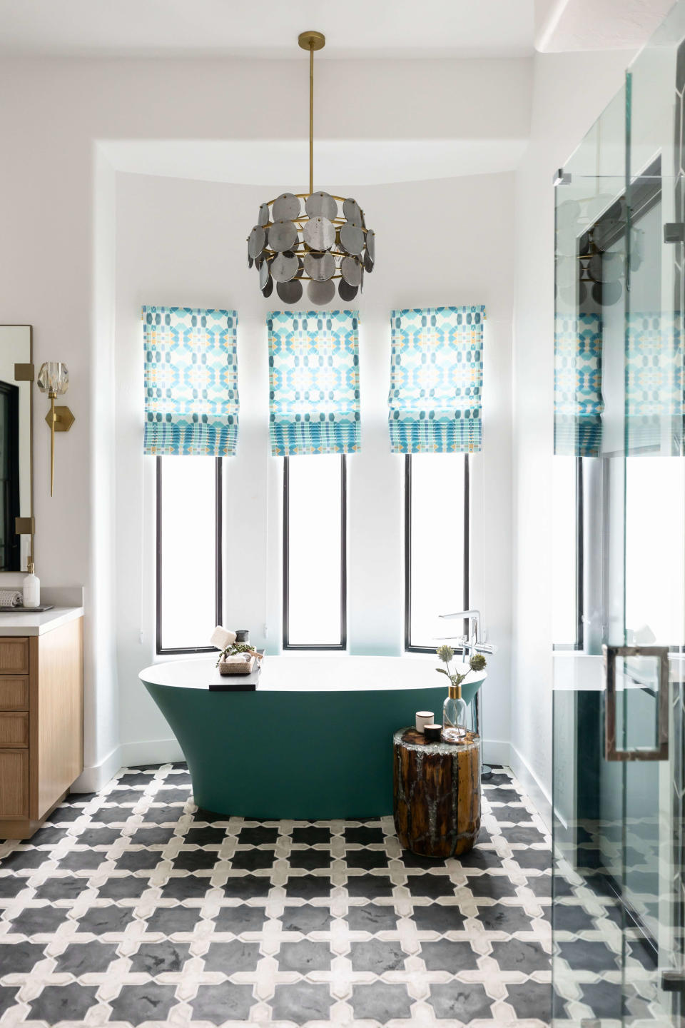 A bathroom with a round, beaded chandelier above the bathtub