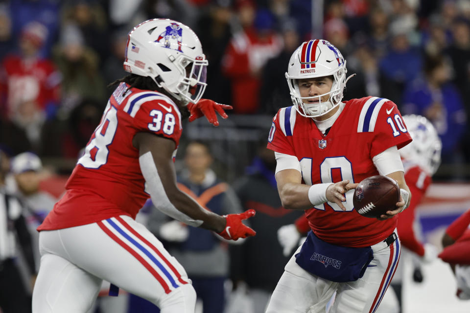 New England Patriots quarterback Mac Jones (10) hands off to running back Rhamondre Stevenson (38) during the first half of an NFL football game against the Buffalo Bills, Thursday, Dec. 1, 2022, in Foxborough, Mass. (AP Photo/Michael Dwyer)