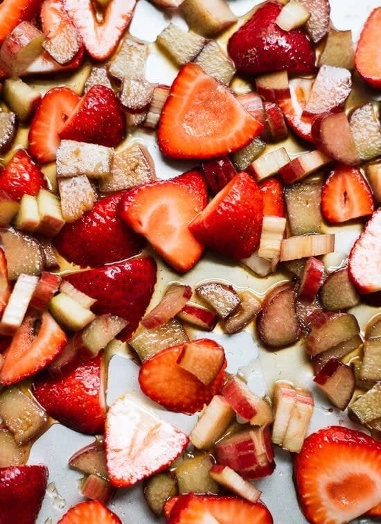 Sliced strawberries and rhubarb pieces spread on a baking tray