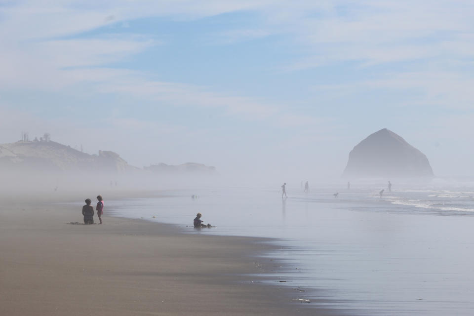 FILE - People walk on the beach at Tierra del Mar, Ore., on, Aug. 17, 2020. The Oregon Coast is featured in a collection of mini-essays by American writers published online by the Frommer's guidebook company about places they believe helped shape and define America. (AP Photo/Andrew Selsky, File)