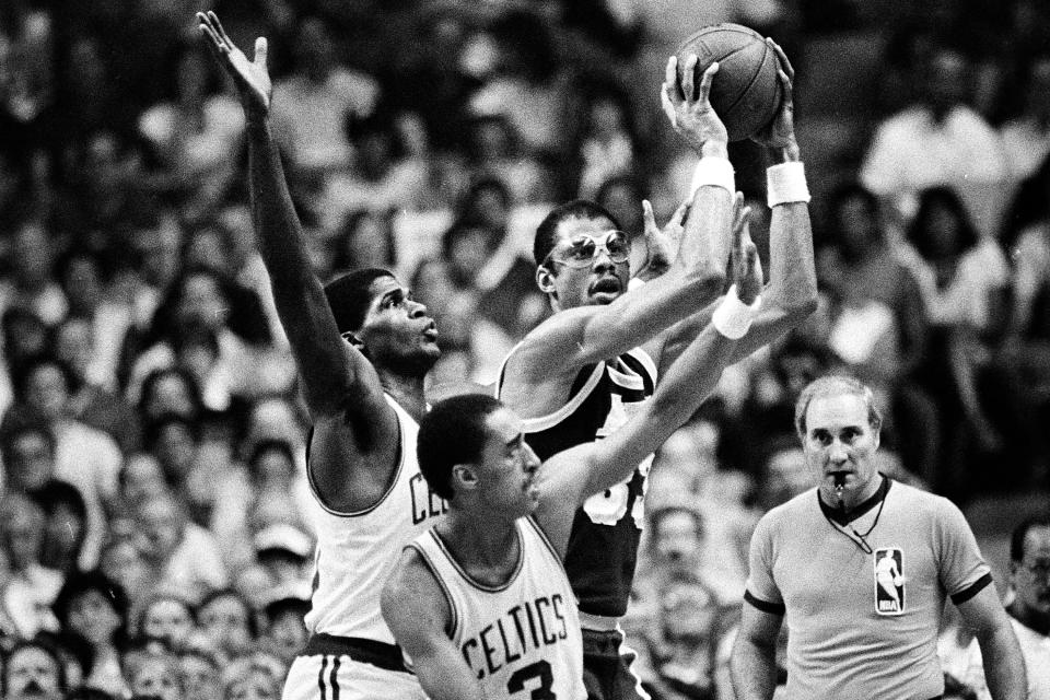 FILE - Los Angeles Lakers center Kareem Abdul-Jabbar (33) looks to pass off the ball as Boston Celtics' Robert Parish, left, and Dennis Johnson defend during first quarter action in game seven of the NBA championship series in Boston, Ma., Tuesday night, June 12, 1984. The Celtics beat the Los Angeles Lakers 111-102 in Game 7 in the first NBA Finals. Abdul-Jabbar, who finished with 29 points and a basket by James Worthy, who had 21. (AP Photo, File)