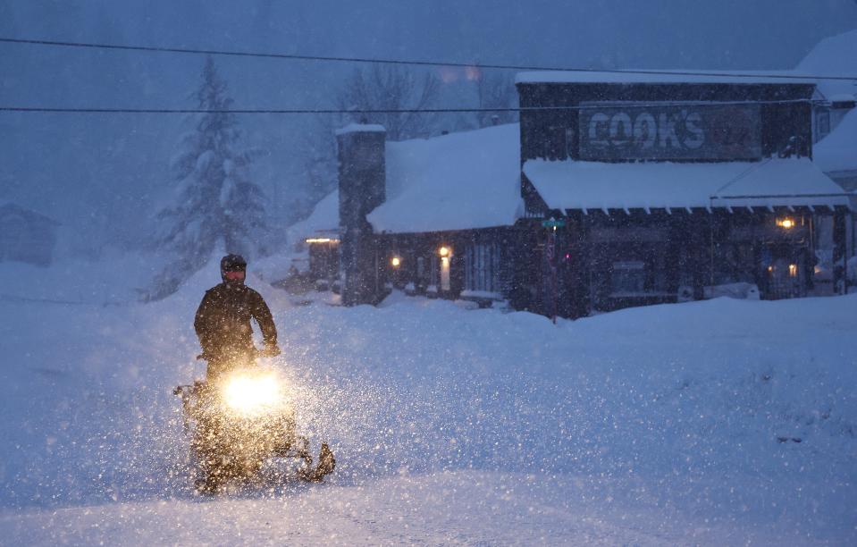 A person rides a snowmobile during a powerful multiple day winter storm in the Sierra Nevada mountains on Tuesday in Truckee, California.