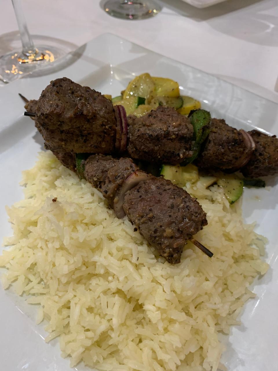 Skewers of chargrilled beef tenderloin are stacked with bell peppers and onions, served over basmati 
rice with a side of zucchini and squash at Laziza.