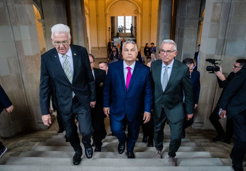 Winfried Kretschmann (L), Minister President of Baden-Wuerttemberg and Thomas Strobl (R), Minister of the Interior of Baden-Wuerttemberg accomapny Viktor Orban (C), Prime Minister of Hungary, as he arrives at the New Palace. Christoph Schmidt/dpa