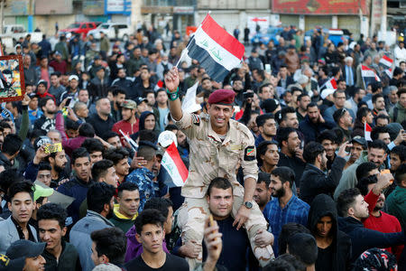 A member of Iraqi security forces carries an Iraqi flag as he celebrates the final victory over the Islamic State at Tahrir Square in Baghdad, Iraq December 10, 2017. REUTERS/Thaier Al-Sudani