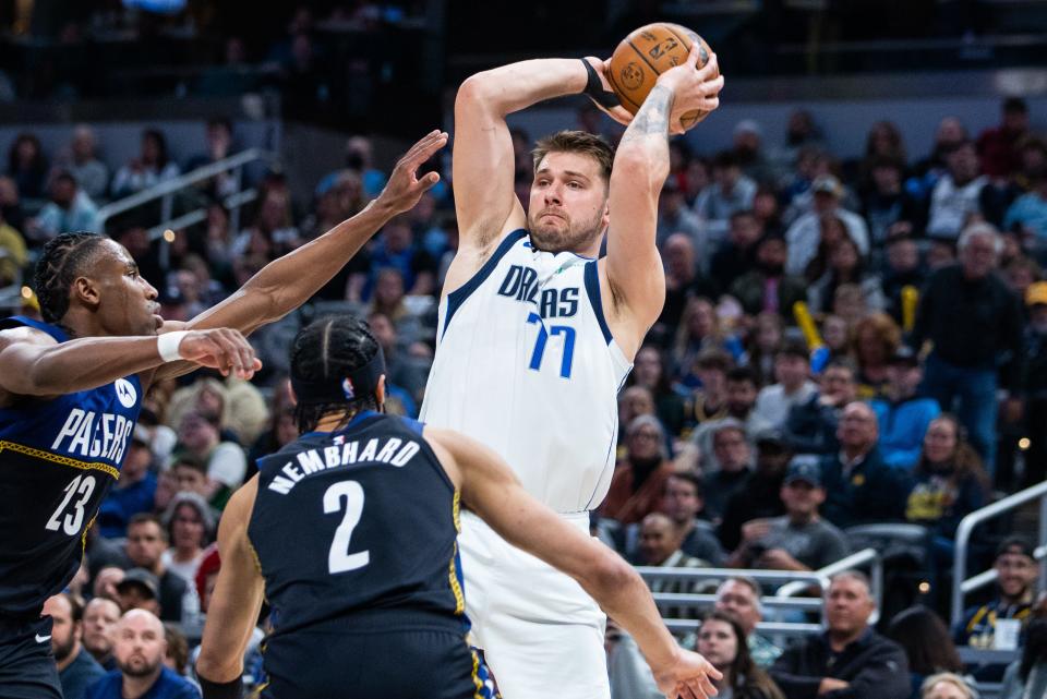 Dallas Mavericks guard Luka Doncic (77) passes the ball while Indiana Pacers guard Andrew Nembhard (2) and forward Aaron Nesmith (23) defend in the second quarter at Gainbridge Fieldhouse.
