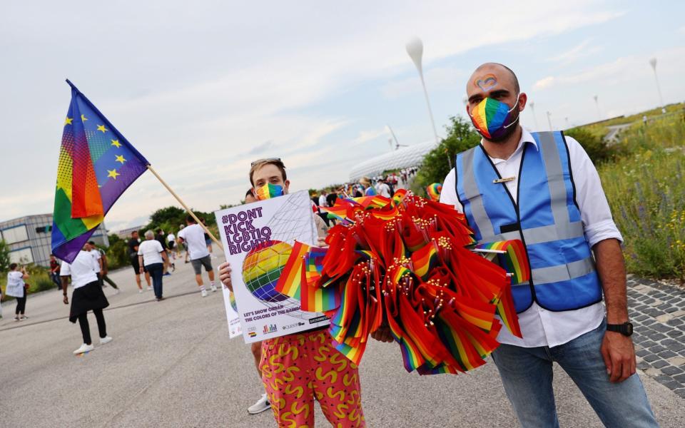 A steward holds rainbow flags outside the stadium  - Reuters