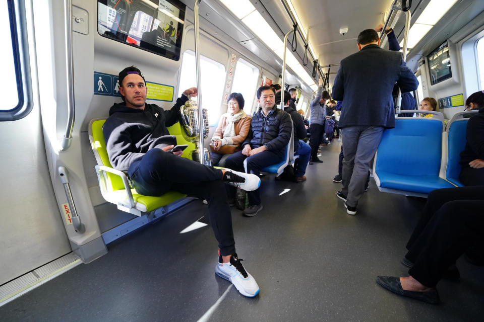 Brooks Koepka rides a BART train with the Wanamaker Trophy
