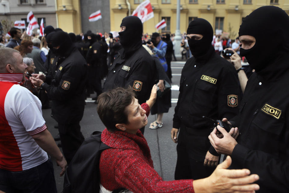 A woman kneels in front of riot police line as they block Belarusian opposition supporters rally in the center of Minsk, Belarus, Sunday, Aug. 30, 2020. Opposition supporters whose protests have convulsed the country for two weeks aim to hold a march in the capital of Belarus. (AP Photo)