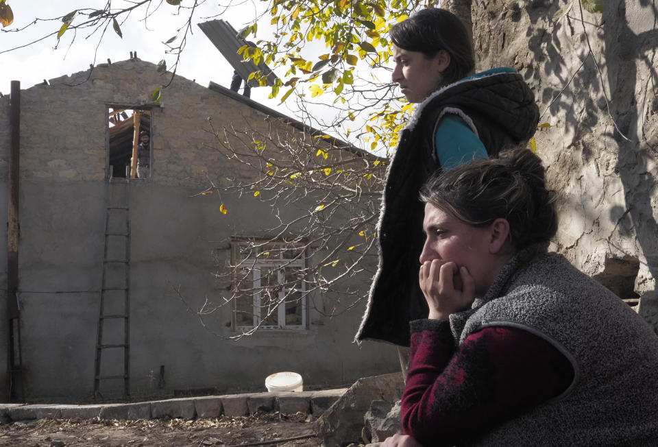 Sirarpi Safaryan, foreground, a relative of Garo Dadevusyan, sits near her house in Kalbajar before leaving the separatist region of Nagorno-Karabakh to Armenia, on Saturday, Nov. 14, 2020. The village is to be turned over to Azerbaijan on Sunday as part of territorial concessions in an agreement to end six weeks of intense fighting with Armenian forces. Hundreds of thousands of Azeris were displaced by the war that ended in 1994. It is unclear when any civilians might try to settle in Karvachar — which will now be known by its Azeri name Kalbajar — or elsewhere. (AP Photo/Dmitry Lovetsky)